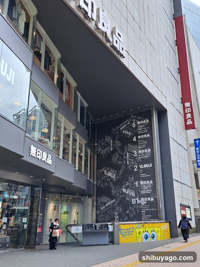 Exterior view of a Muji store with visible signage in Japanese and English, glass storefronts, and a directional map on the wall.