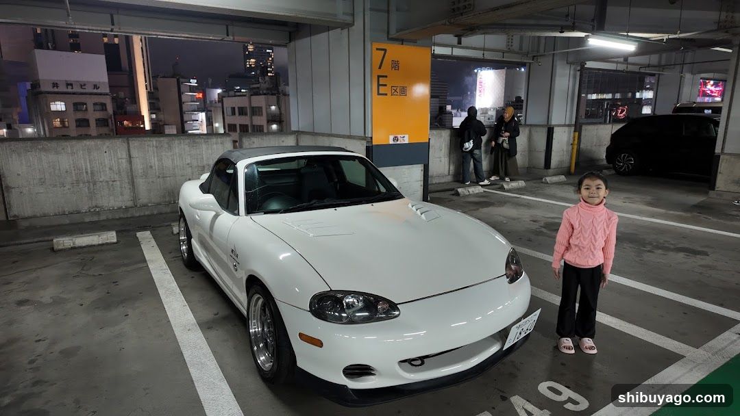 White convertible car in parking garage with child standing nearby