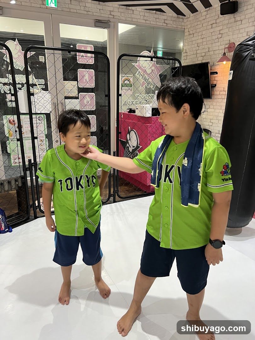 Two boys in green 'TOKYO' shirts at a gym or training center