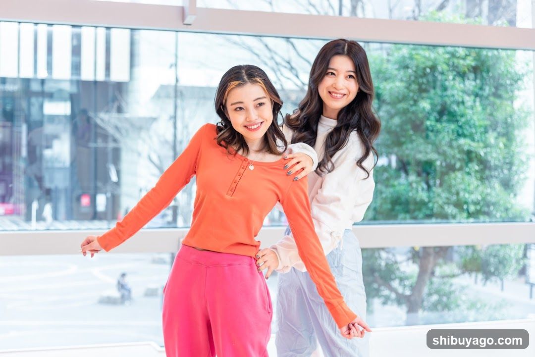Two women posing indoors near a window