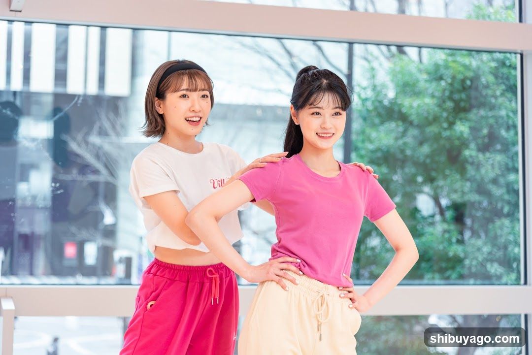 Two women in casual sportswear posing indoors near a window
