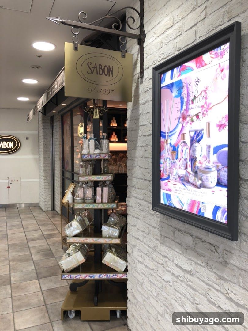 A storefront with a hanging sign reading 'SABON est.1997'. A display rack holds various packaged products, and an illuminated poster on the wall advertises 'Tokyo Celebration' featuring floral designs and bottles.