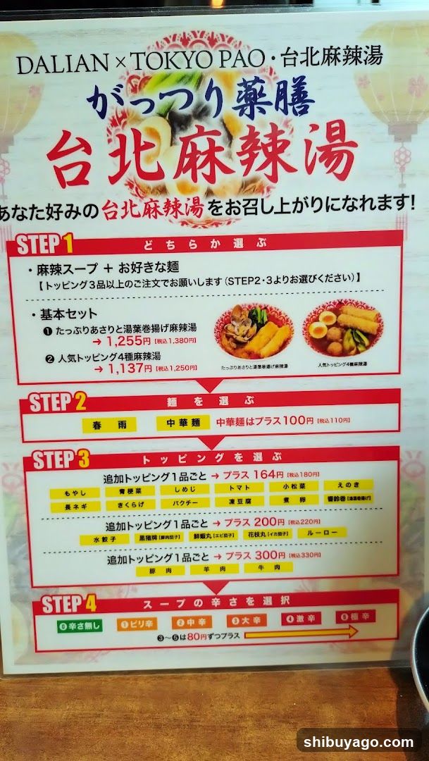 A printed menu board advertising a collaboration between Dalian and Tokyo Pao, featuring a 'Taipei Spicy Hot Pot' (台北麻辣湯). The menu outlines four steps to customize the order: selecting soup base or noodles, choosing noodle type, adding toppings with prices, and selecting spice level.