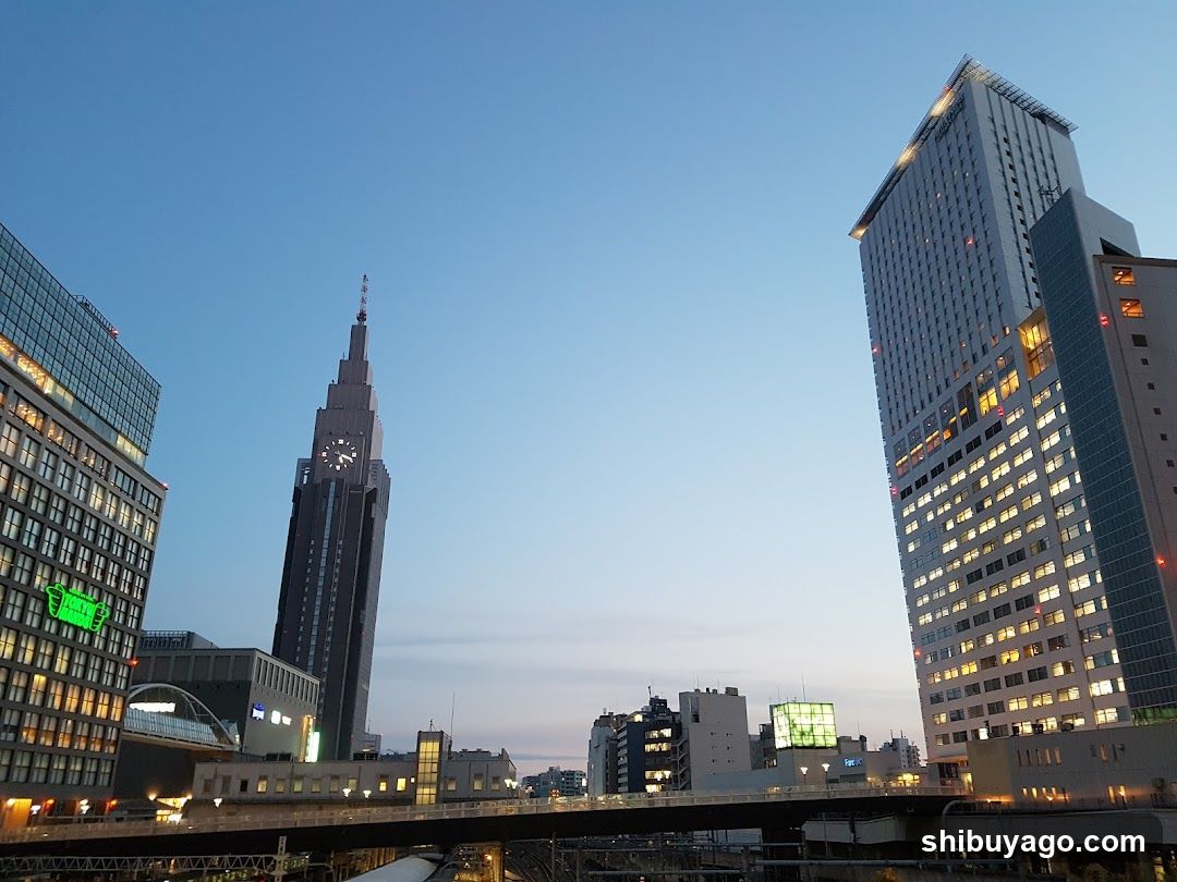 Cityscape at dusk with illuminated buildings and a clock tower