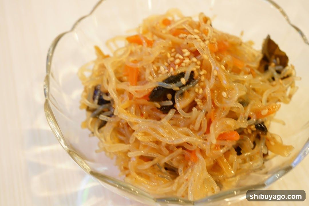 Glass Bowl of Stir-Fried Noodles with Vegetables and Sesame Seeds