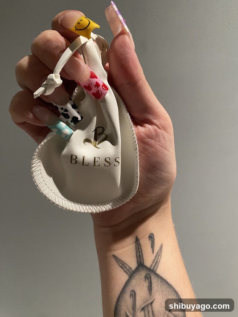 Hand holding a small pouch with colorful nails and tattoo visible