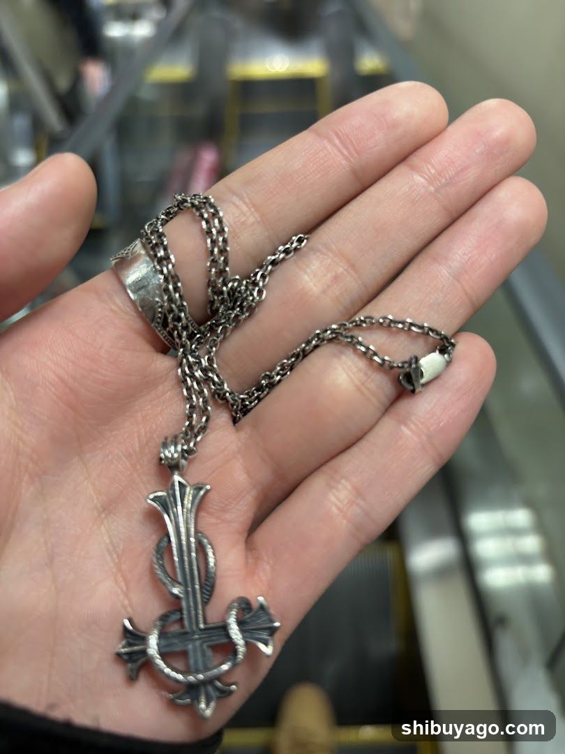Hand holding silver necklace with cross pendant