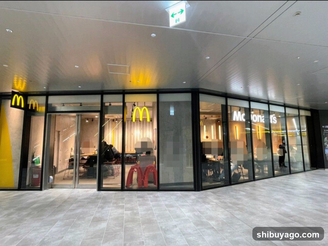 A modern McDonald's restaurant with glass facade, visible signage including the golden arches logo and 'McDonald's' lettering on the window. Interior seating area is partially visible through large windows.
