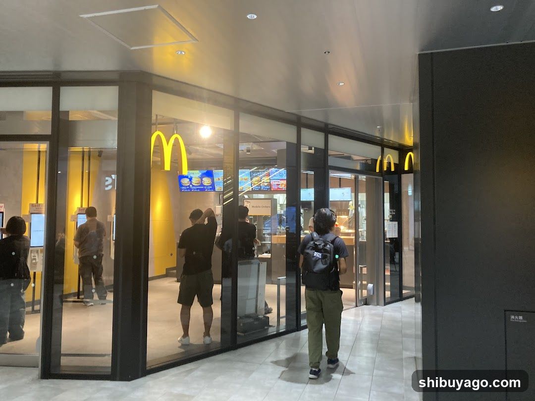Photo of physical exterior entrance/storefront facade with visible shop signage (yellow M logo) on building glass panels. Interior shows customers at self-service kiosks and ordering counter.