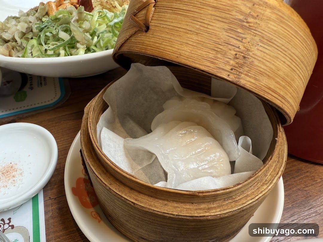 A close-up of a bamboo steamer containing translucent dumplings wrapped in parchment paper, with a bowl of shredded cabbage salad visible in the background.