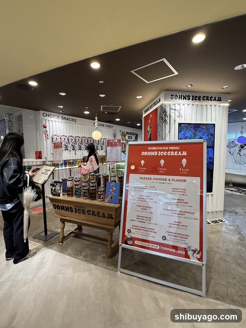 Interior of a Johns Ice Cream shop featuring customers browsing ice cream products, a menu board listing flavors and prices, and promotional displays.