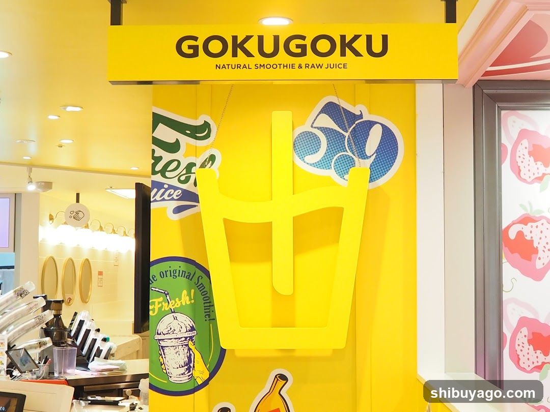Bright yellow storefront with large 'GOKUGOKU' sign above entrance, featuring a giant juice glass cutout and colorful fruit graphics on the wall.