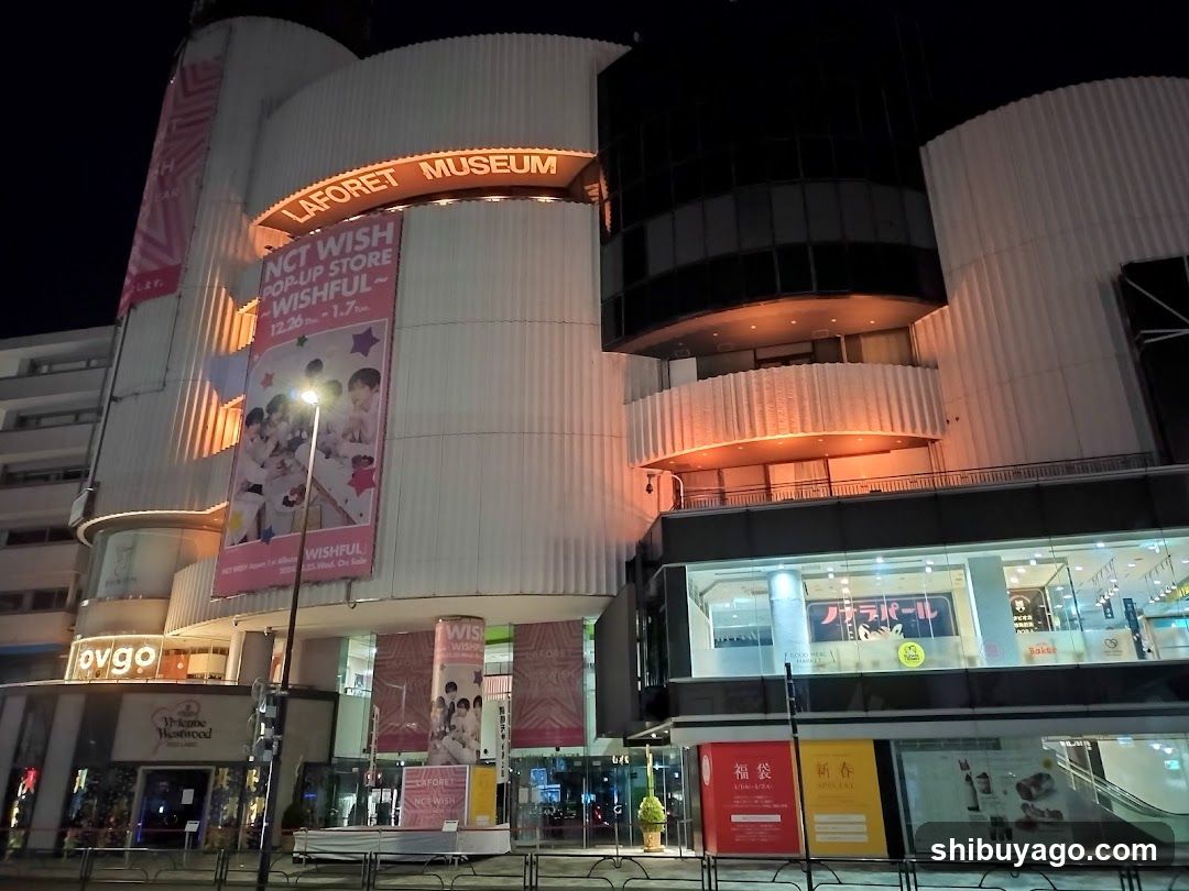 Night view of a commercial building with illuminated signage and advertisements.