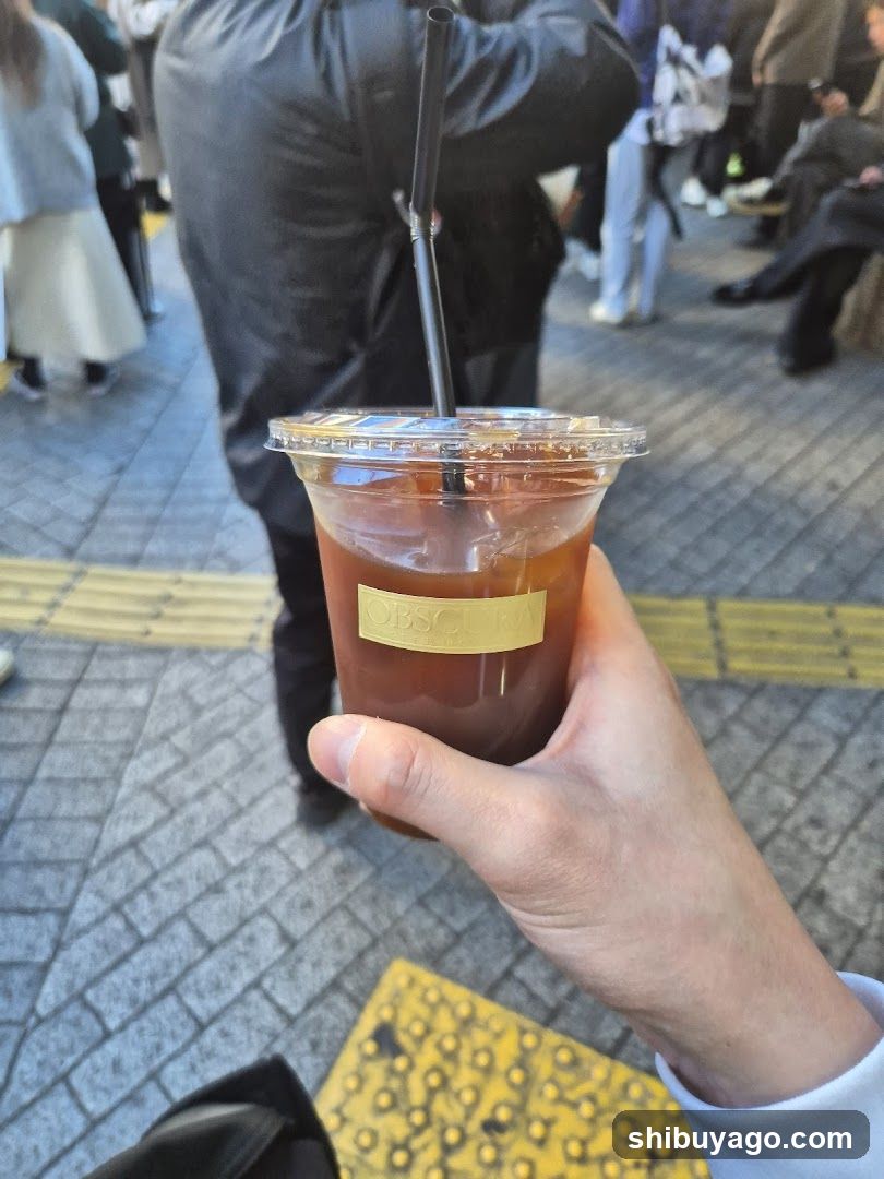 Hand holding iced coffee in public space