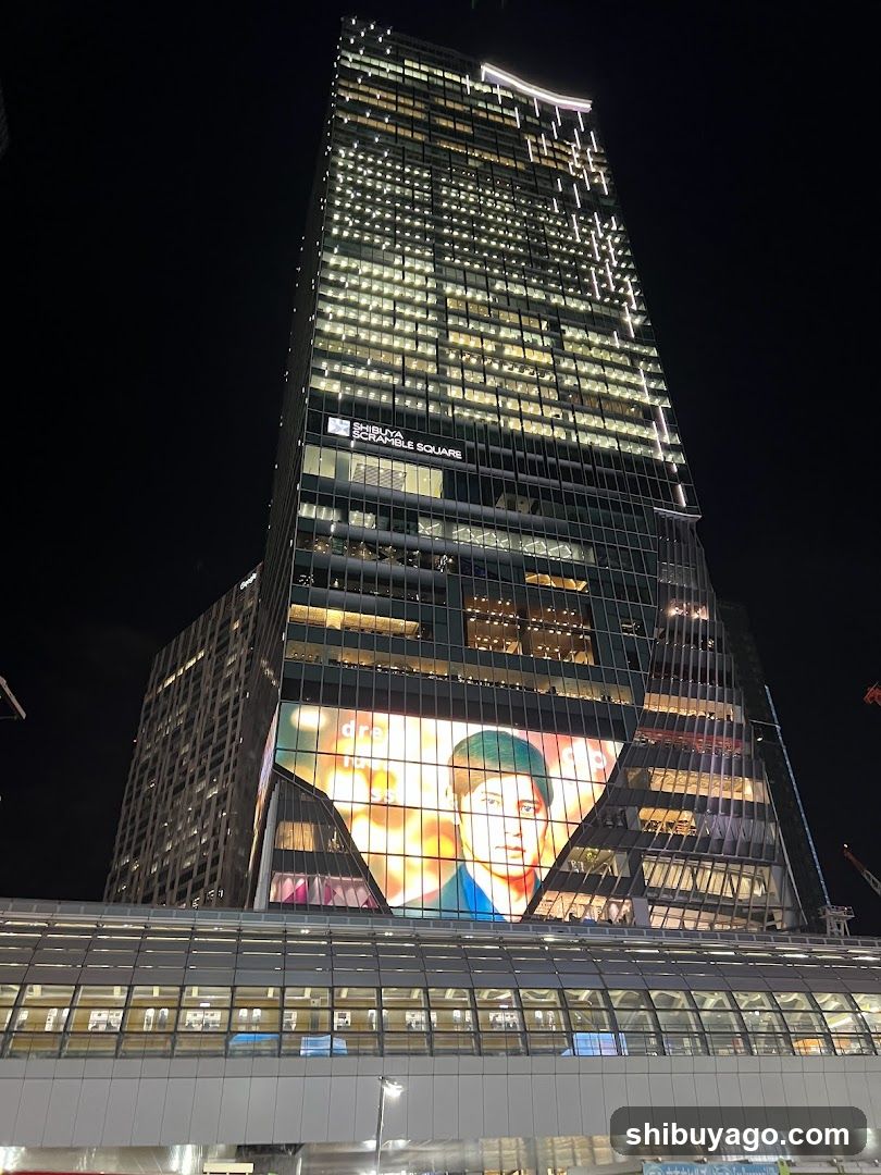 Night view of a tall building with illuminated signage and large advertisement screen