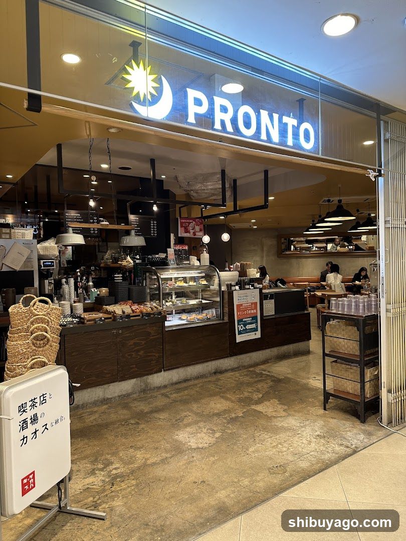 A brightly lit shop entrance with a large illuminated 'PRONTO' sign above the glass facade. Inside, customers are seated at tables near a counter displaying baked goods in a glass case. A white sign on the left reads '喫茶店と酒場のカオス'.