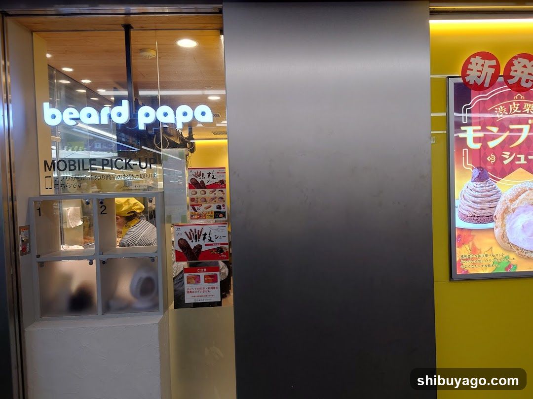 Photo of the exterior entrance of a beard papa shop, showing glass doors with illuminated signage and a mobile pick-up area.