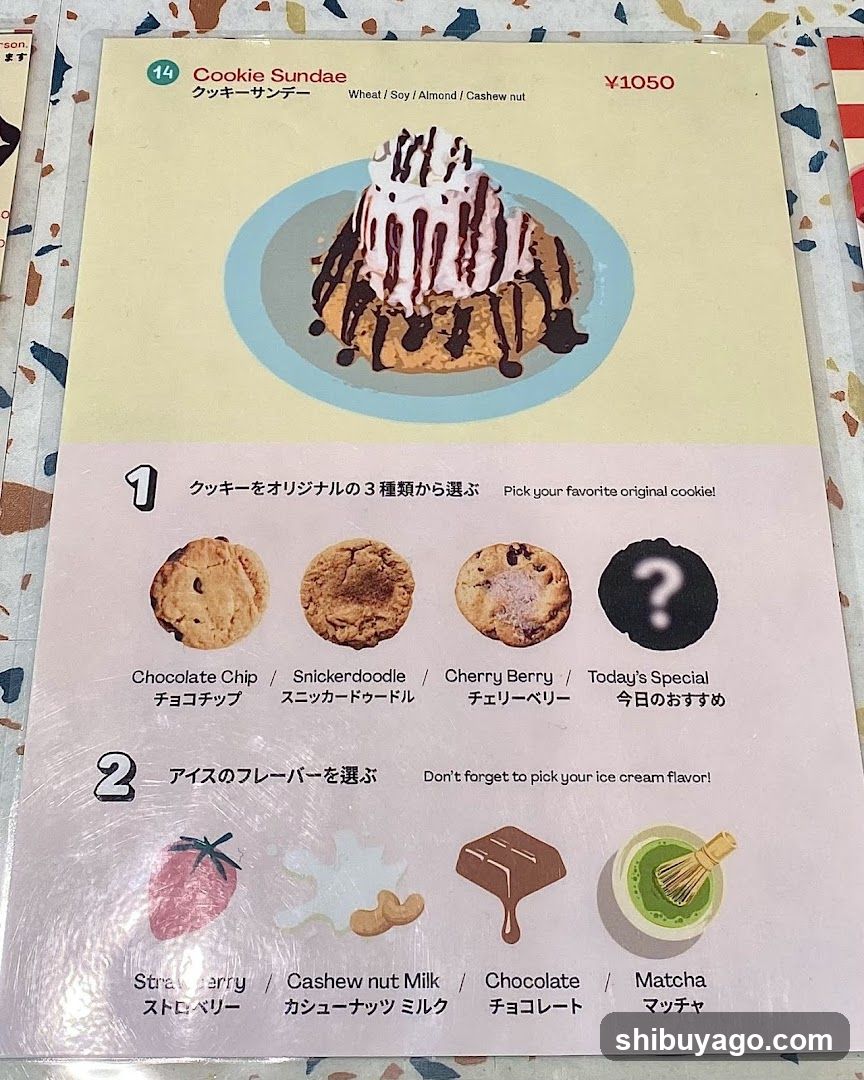 A close-up of a Japanese-style dessert menu page featuring 'Cookie Sundae' priced at ¥1050. The page shows an image of the sundae with cookie base, whipped cream, and chocolate drizzle. Below are options to choose from three original cookies (Chocolate Chip, Snickerdoodle, Cherry Berry) plus today's special, and four ice cream flavors (Strawberry, Cashew nut Milk, Chocolate, Matcha). Text includes English and Japanese translations.