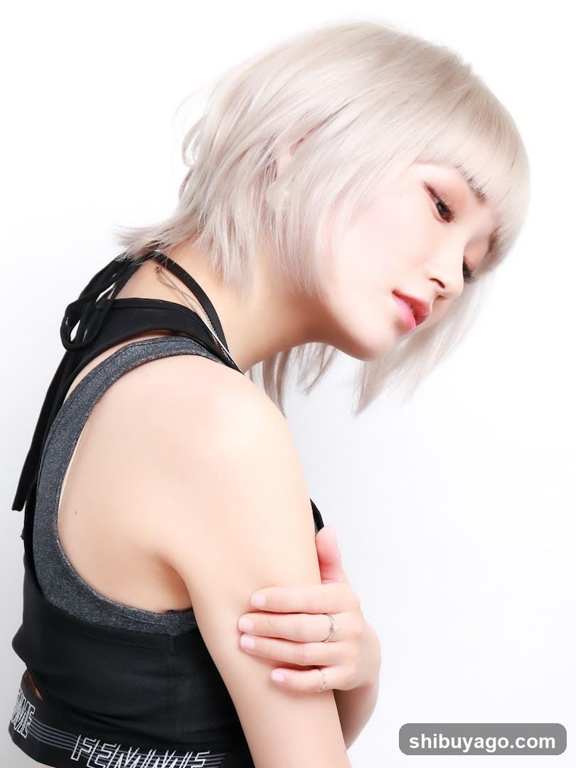 Portrait of a person with short blonde hair wearing a black and gray tank top, holding their shoulder.