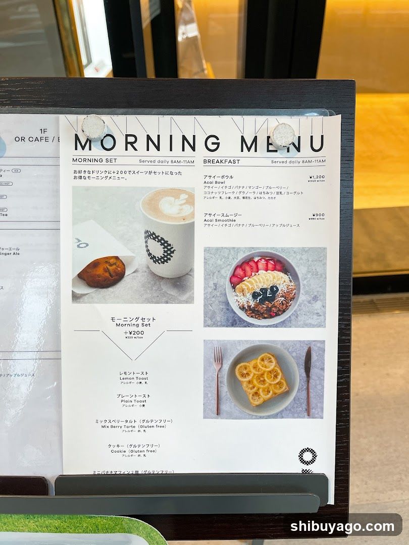 A printed menu board displaying breakfast and morning set options with photos of food items, prices in yen, and Japanese text descriptions.