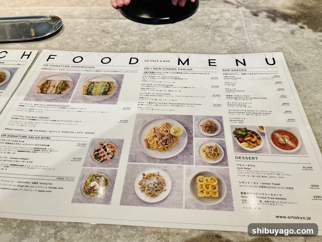 A printed menu from Or Tokyo, featuring sections like Signature Sandwiches, New Cinema Parlour, Bar Snacks, and Dessert. Visible items include Tuna Salad Bowl (¥1,400), Curry Burger (¥1,500), Lemon Toast (¥690), and various bar snacks with prices ranging from ¥380 to ¥4,200.