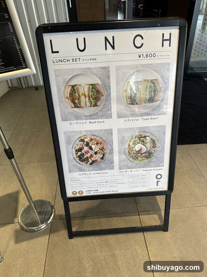 A standing menu board displaying four lunch set options with images and names in Japanese and English, priced at ¥1,600 each.