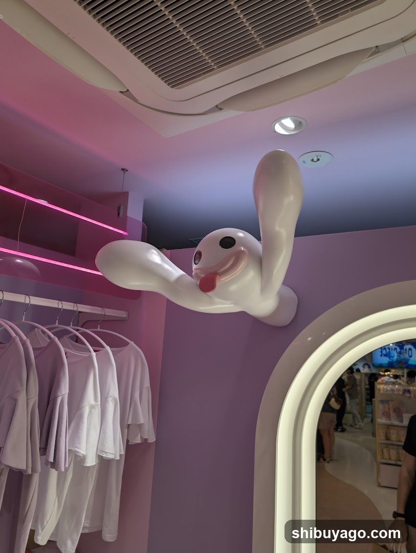 Interior of a pink-themed store with hanging clothes and a cartoon character decoration