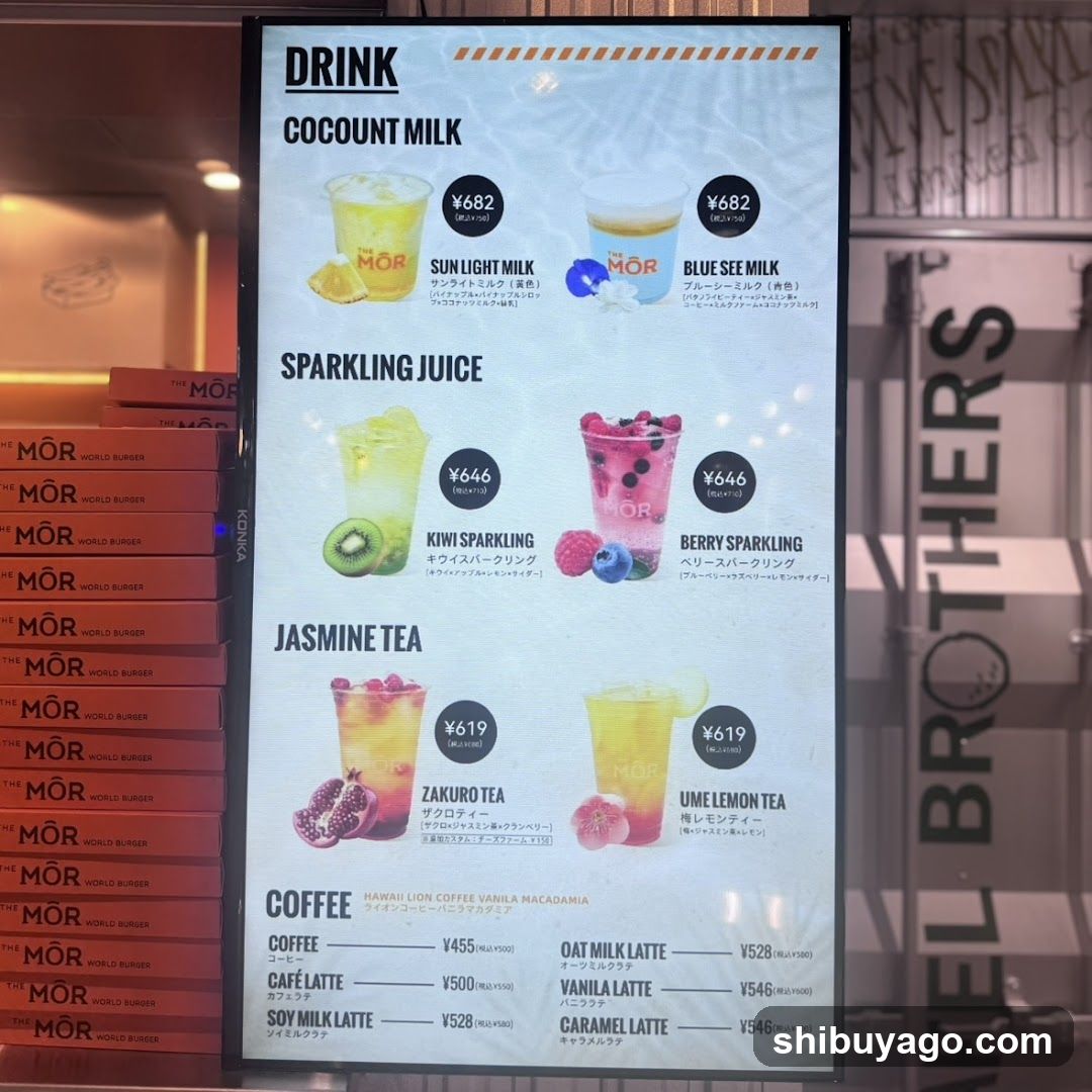 Digital menu board displaying drinks and coffee options with prices in yen, visible on a storefront wall next to stacked branded boxes.