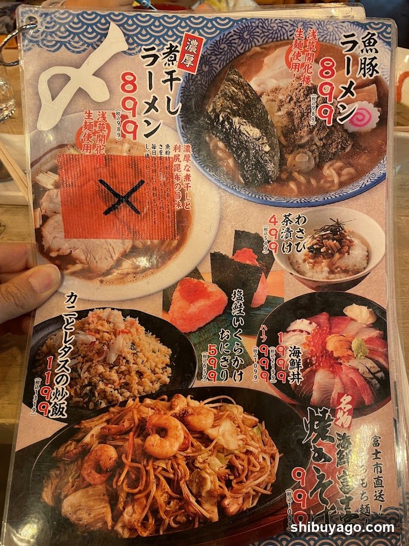 A close-up of a Japanese restaurant menu featuring various dishes including ramen, fried rice, sashimi, and stir-fried noodles with shrimp.