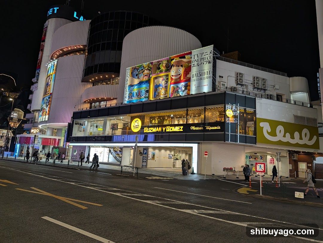 Night street scene with illuminated buildings and storefronts