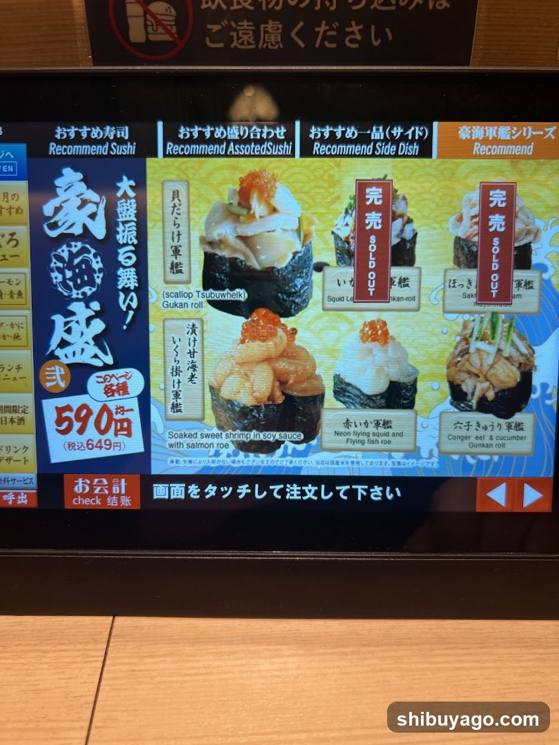 A digital menu board showing sushi and side dish recommendations, featuring images of gunkan rolls with salmon roe, squid, and other toppings. Prices are listed in yen.